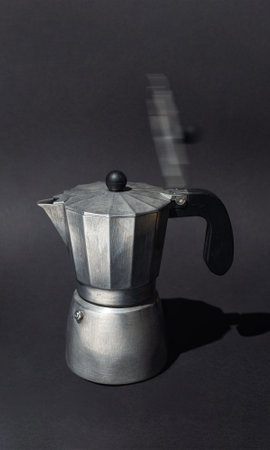 An old aluminum Moka pot with a motion-blurred lid, captured against a dark background, symbolizing morning coffee energy and routine.の写真素材
