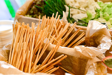 Golden crispy breadsticks displayed in a rustic paper-lined basket, perfect for appetizers, buffets,...