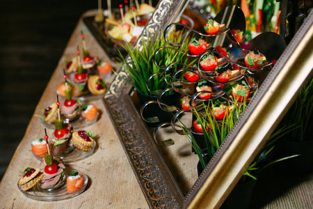Elegant table setup featuring gourmet hors d'oeuvres with creative presentation in spoons and glass plates, perfect for events.の写真素材