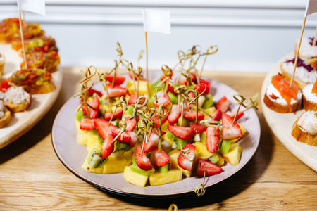 Fresh fruit skewers with pineapple, kiwi, and strawberries served on a plate, perfect for party or catering events.の写真素材