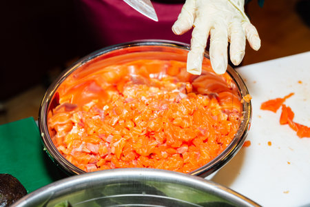 Finely diced raw salmon prepared in a stainless steel bowl, ready for sushi, tartare, or seafood...