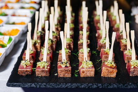 Close-up of gourmet seared tuna cubes topped with relish and served on wooden skewers as elegant hors d'oeuvres at event.の写真素材