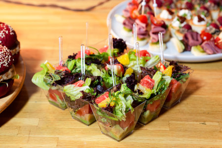 Small clear cups filled with fresh mixed greens, grapefruit, orange, and avocado, served as...