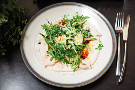 Plate of vitello tonnato topped with arugula, cherry tomatoes, and shredded cheese, served on creamy tuna sauce with balsamic glaze.の写真素材