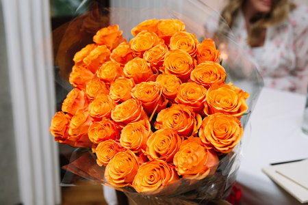 A stunning bouquet of vibrant orange roses wrapped in transparent cellophane, perfect for gifts, celebrations, or romantic occasions.の写真素材