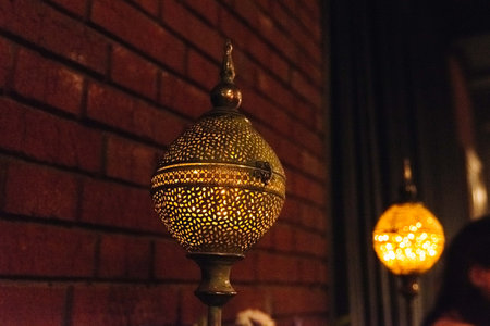 Decorative vintage lantern with intricate perforated metal design glowing warmly in a cozy, dimly...