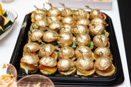 Luxury appetizer tray featuring gourmet mini burgers topped with edible gold leaf buns, ideal for upscale parties or events.の写真素材