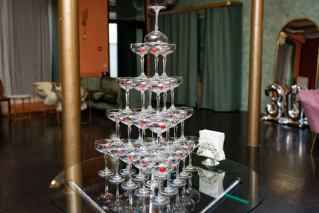 Stacked champagne coupe glasses with cherries on a glass table, prepared for a 30th birthday celebration in a decorated venue.の写真素材