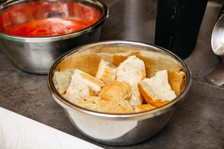 Chunks of fresh white bread placed in a stainless steel bowl, likely prepared for a cooking or baking recipe.の写真素材