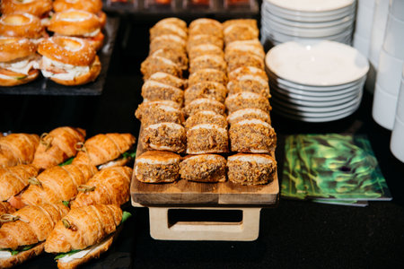Rows of nut-coated sandwich cookies arranged neatly on a wooden tray, part of a dessert and pastry buffet display at an event.の写真素材