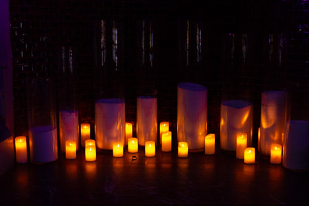 Multiple glowing candles create a warm, intimate ambiance in a dark room, ideal for romantic or festive evening scenes.の写真素材