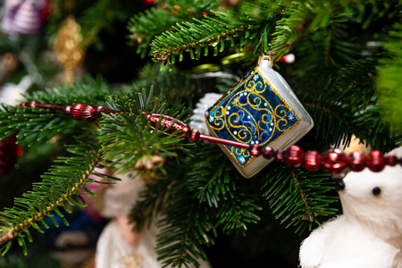 Detailed view of a decorated Christmas tree with a blue and gold ornament, red beads, and festive...