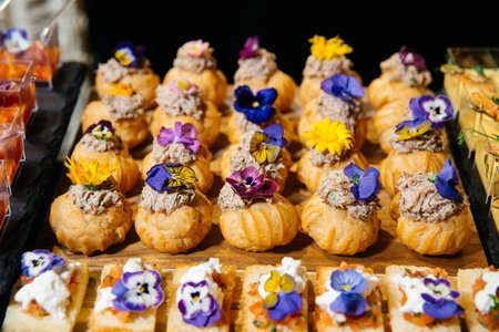 Elegant puff pastry bites filled with meat mousse and topped with colorful edible flowers, ideal for...