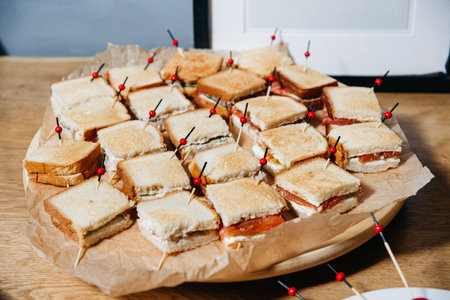 Assorted mini sandwiches arranged on a tray, each secured with a skewer, ideal for events, parties,...