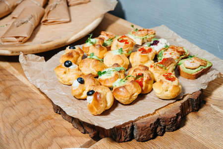 Selection of savory pastries, canapÃ©s, and crostini with toppings like cream, shrimp, and caviar served on wooden platter.の写真素材