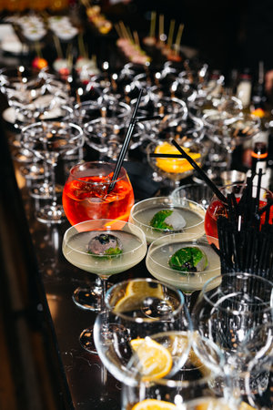 Vibrant cocktails and garnished drinks arranged on a glossy bar counter at an upscale event or party setting.の写真素材