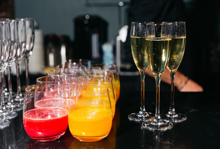Glasses of red and orange juice alongside champagne flutes filled with sparkling wine, prepared for a festive celebration or party.の写真素材