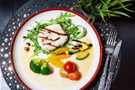 Elegant plated burrata cheese served on arugula with broccoli, zucchini, orange slices, cherry tomatoes, and balsamic glaze.の写真素材