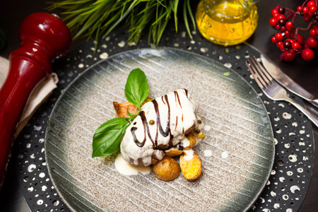 Elegant plated steak served with roasted baby potatoes, creamy peppercorn sauce, and fresh basil on a rustic ceramic dish.の写真素材