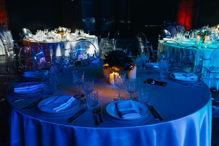 Luxurious banquet setup with crystal glassware, floral centerpieces, and candlelight creating a romantic and upscale evening ambiance.の写真素材