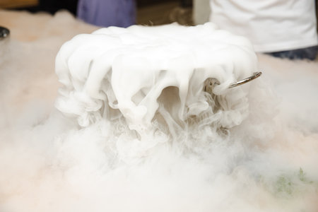 Dense white vapor billows from a metal pot, likely using liquid nitrogen for culinary or scientific demonstration purposes.の写真素材