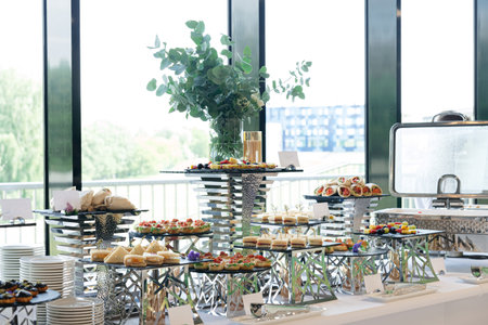 Beautifully arranged buffet table featuring a variety of finger foods, sandwiches, wraps, and desserts, perfect for events or catering services.の写真素材