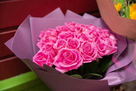 Close-up of a large bouquet of fresh pink roses wrapped in soft lavender paper, perfect for romantic or celebratory occasions.の写真素材
