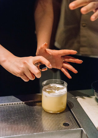 A bartender finishes a whiskey sour cocktail with a fine aromatic spray, adding a final touch of flavor and flair.の写真素材