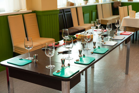 Long table prepared for a bartending class with glassware, jiggers, spoons, and cutting boards...