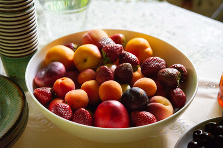 A vibrant assortment of summer fruits including strawberries, peaches, and plums nestled in a white...