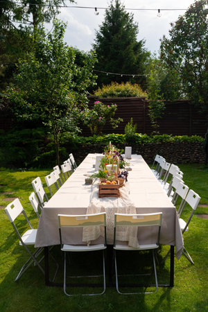 A beautifully arranged table in a lush garden setting, perfect for an outdoor gathering. white...