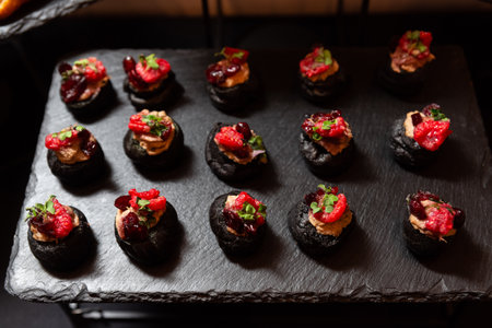 A selection of gourmet canapÃ©s artfully arranged on a slate platter. each bite-sized treat is...