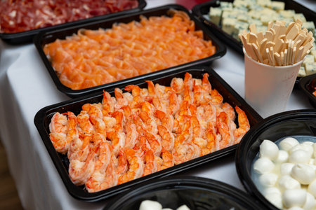 A beautifully arranged platter showcasing an assortment of seafood including shrimp and salmon, paired with cubes of cheese and wooden utensils, perfect for a buffet or event.の写真素材