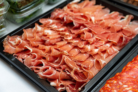 A close-up view of a beautifully arranged cured meat platter featuring thinly sliced meats. ideal for gourmet food presentations or culinary events.の写真素材