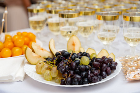 A sophisticated arrangement featuring a variety of fresh fruits and elegant champagne glasses. ideal for celebrations, the table setting combines luxury and style.の写真素材