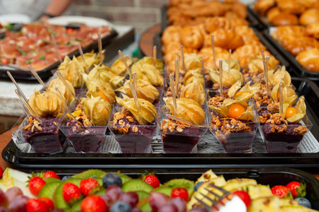 An enticing array of desserts featuring various sweets such as berries, pastries, and physalis-topped treats. perfect for celebrations or gatherings, showcasing a vibrant mix of colors.の写真素材