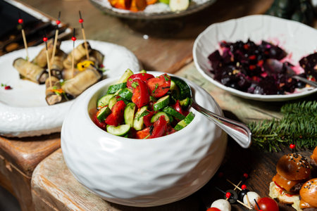 A white ceramic bowl filled with fresh cucumber and tomato salad with herbs sits on a rustic wooden...
