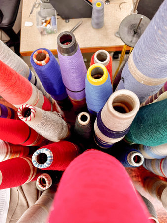 Bobbins filled with colorful threads adorn the sewing table, ready to weave vibrant patterns into...