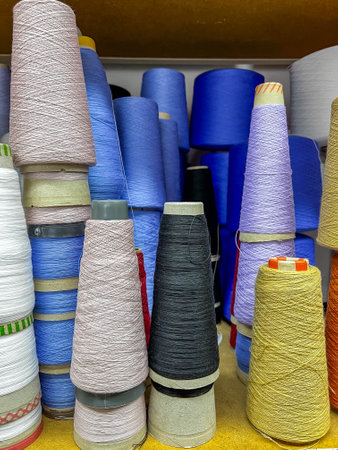 Bobbins filled with colorful threads adorn the sewing table, ready to weave vibrant patterns into...
