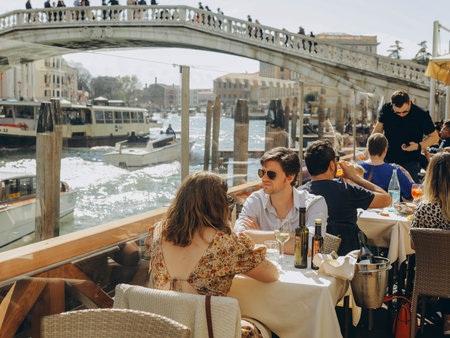 VENICE, ITALY - April 2. 2023: People are sitting at the outside terrace of a small cafe in Venice,...
