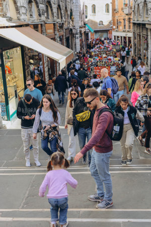 Venice, Italy - Italy 2, 2023: Crowds of tourists strolling on the cobblestone alley near Grand...