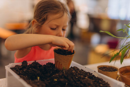 Girl planting seeds for seedlings in small recyclable peat pots, seedling container.Children learn to growの写真素材