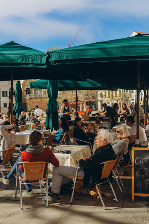 VENICE, ITALY - April 2. 2023: People are sitting at the outside terrace of a small cafe in Venice, Italy.のeditorial素材