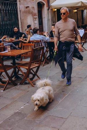 Venecia, Italy-April 2, 2023: Senior Man Enjoying Time Outside with a Pet Dog,のeditorial素材