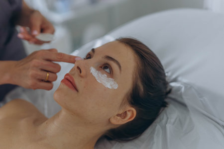 A professional beautician injects Botox into the face of a young womanの写真素材