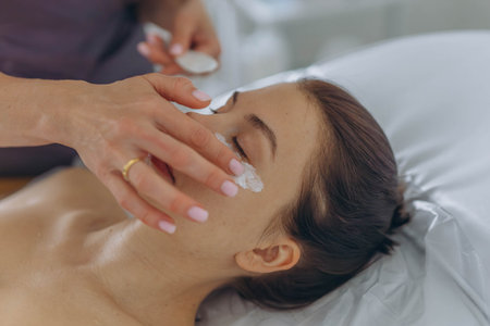 A professional beautician injects Botox into the face of a young womanの写真素材