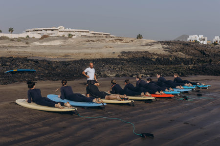 Canary Island, Tenerife-December14,2023.surfers going for surfing in the ocean.Coach show how to...