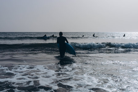 young guy surfers going for surfing in the ocean.