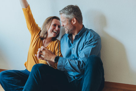 A happy couple is having fun at home while sitting on the floor.の写真素材