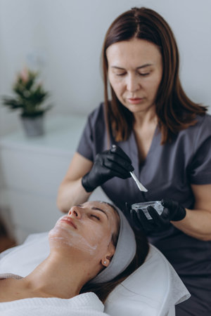 Cosmetologist performs a facial peeling procedure on a young woman. High quality photoの写真素材